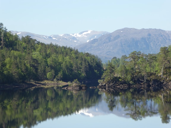A serene lake reflecting surrounding mountains under a clear sky.