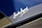 A close-up view of a car's surface showcasing a shiny metallic signature engraved on a sleek blue and carbon fiber material. The script style of the signature is elegant and prominently displayed.