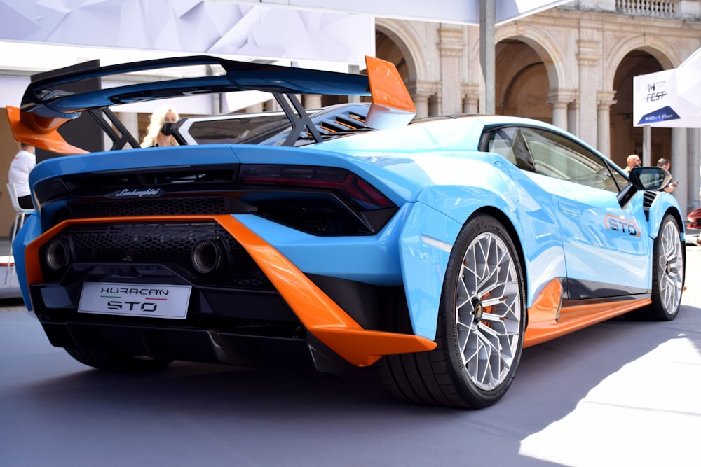 a blue and orange sports car parked in front of a building