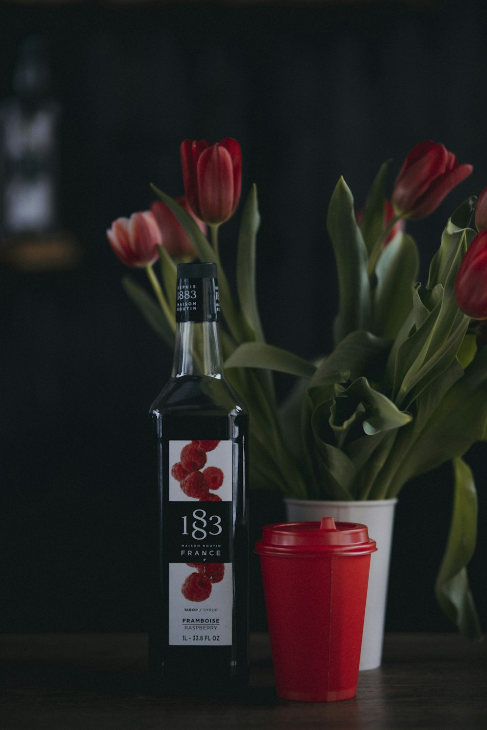 a bottle of liquor next to a vase with flowers