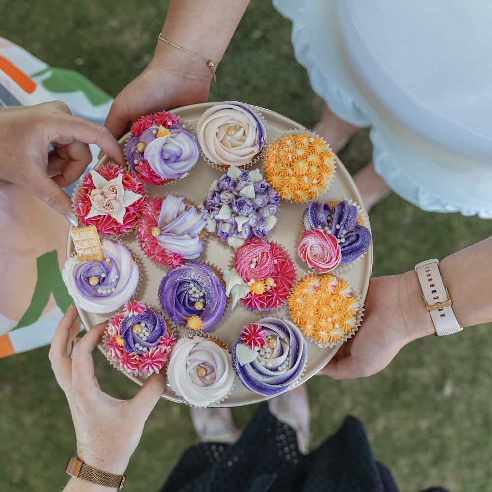 a group of people holding a plate of cupcakes