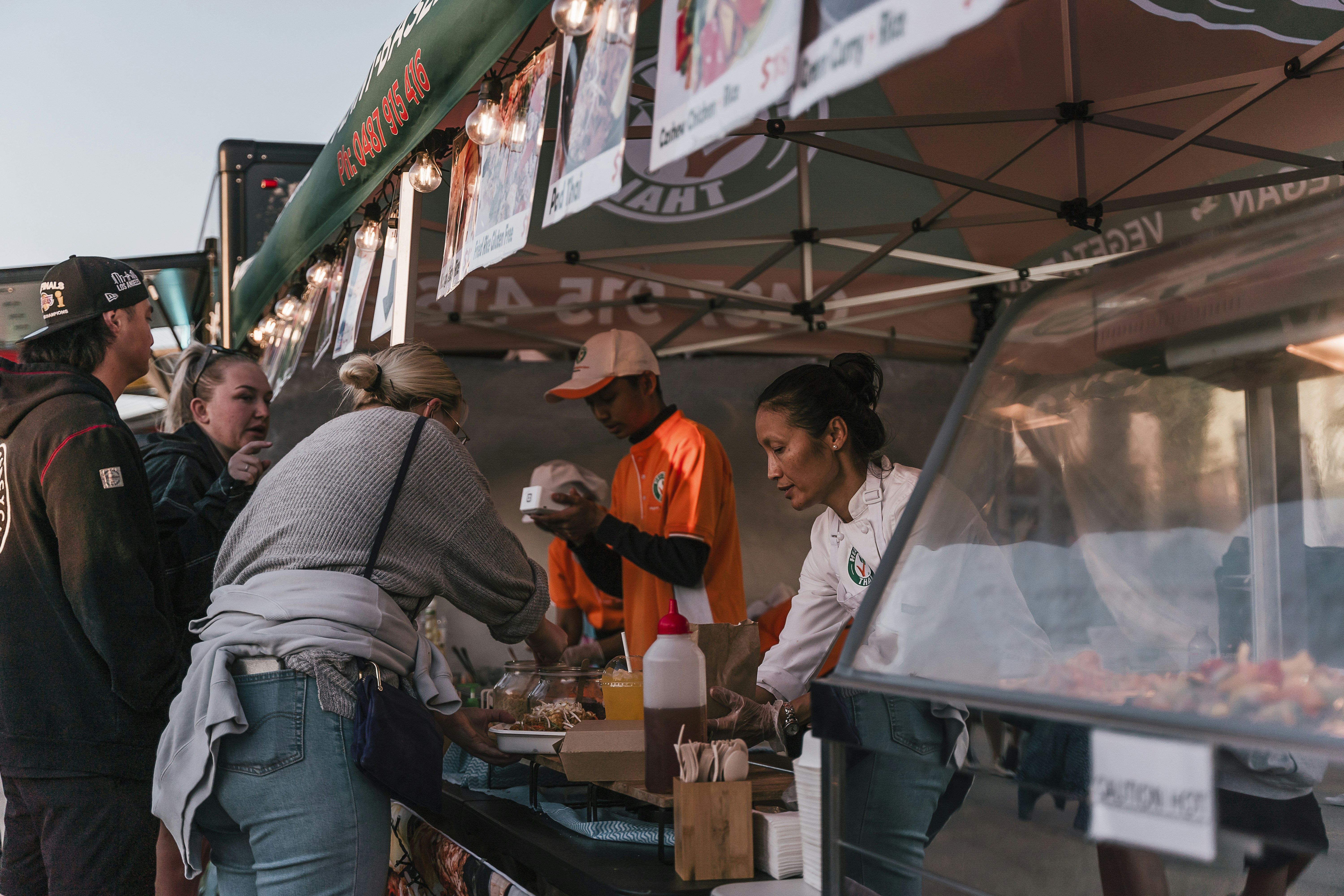 a group of people standing around a food stand