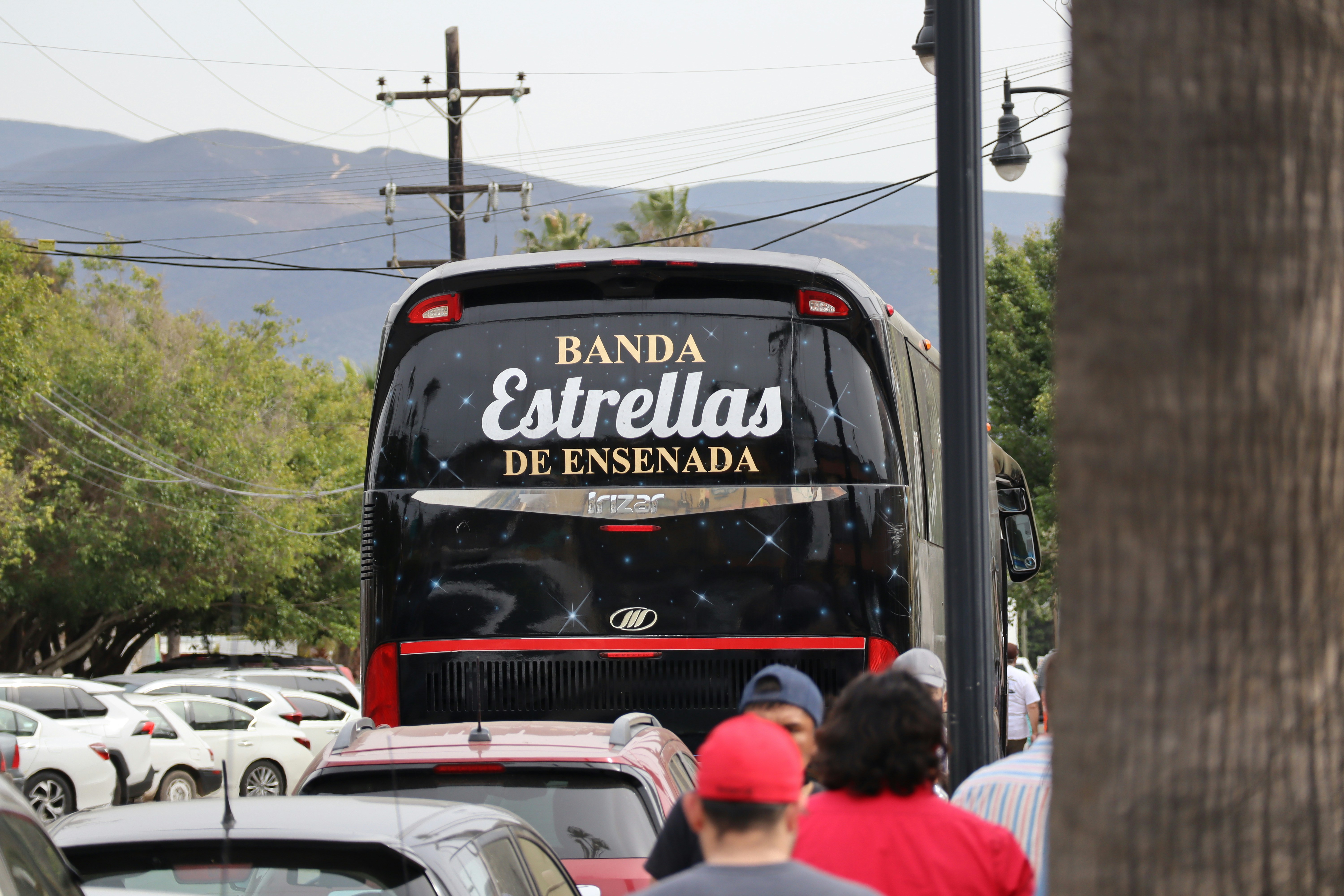 a black bus driving down a street next to a forest