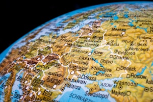 A detailed close-up of a colorful world globe featuring a focus on Eastern Europe. Various country names and cities, such as Warsaw, Budapest, and Moscow, are prominently labeled along with roads and bodies of water. The map includes topographical features with different shades for better differentiation.