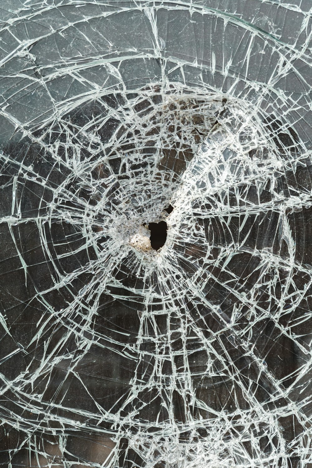 a cracked glass window with a hole in it