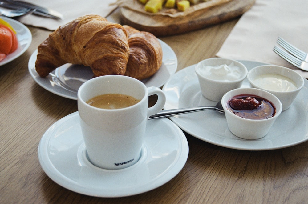 a table topped with plates of food and cups of coffee