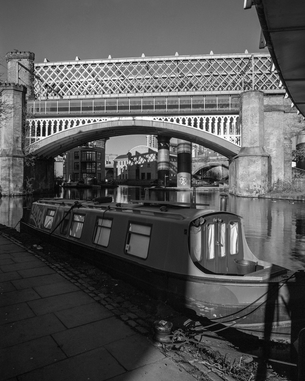 a black and white photo of a boat under a bridge