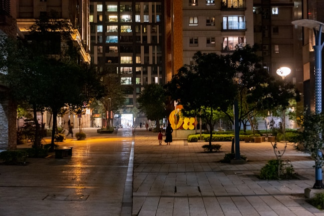 Nighttime scene of a well-lit, accessible pedestrian pathway in a dense urban area.