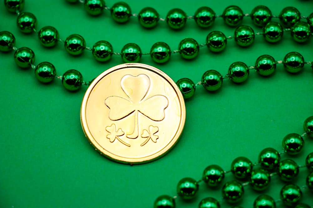 a green beaded necklace with a gold coin on it