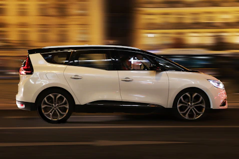 a white car driving down a street at night