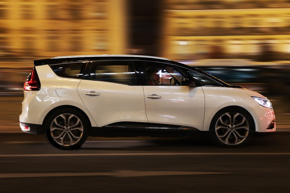 a white car driving down a street at night