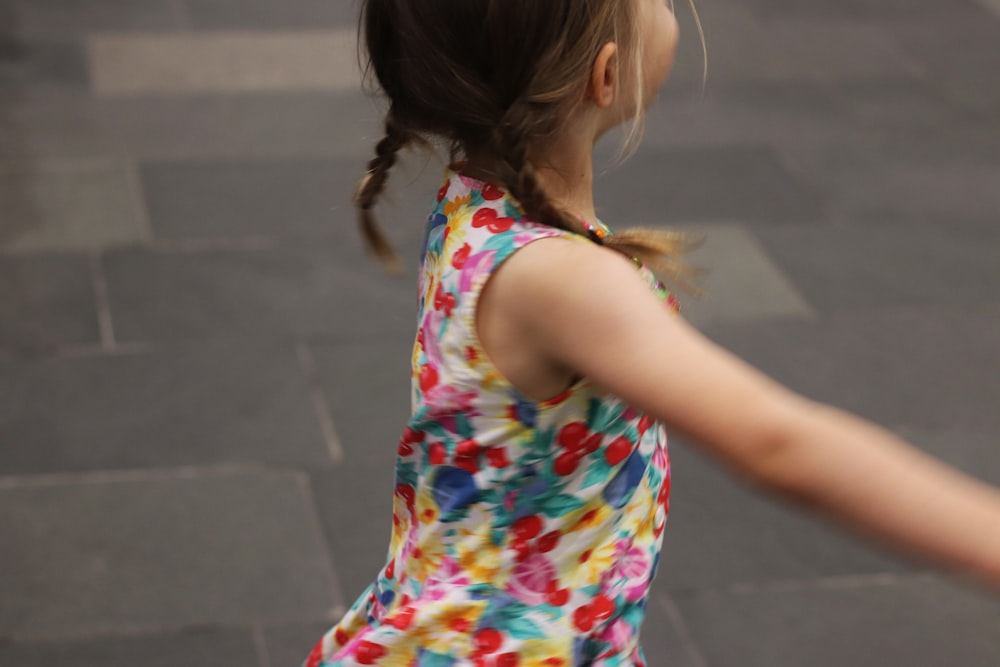 a little girl in a colorful dress throwing a frisbee