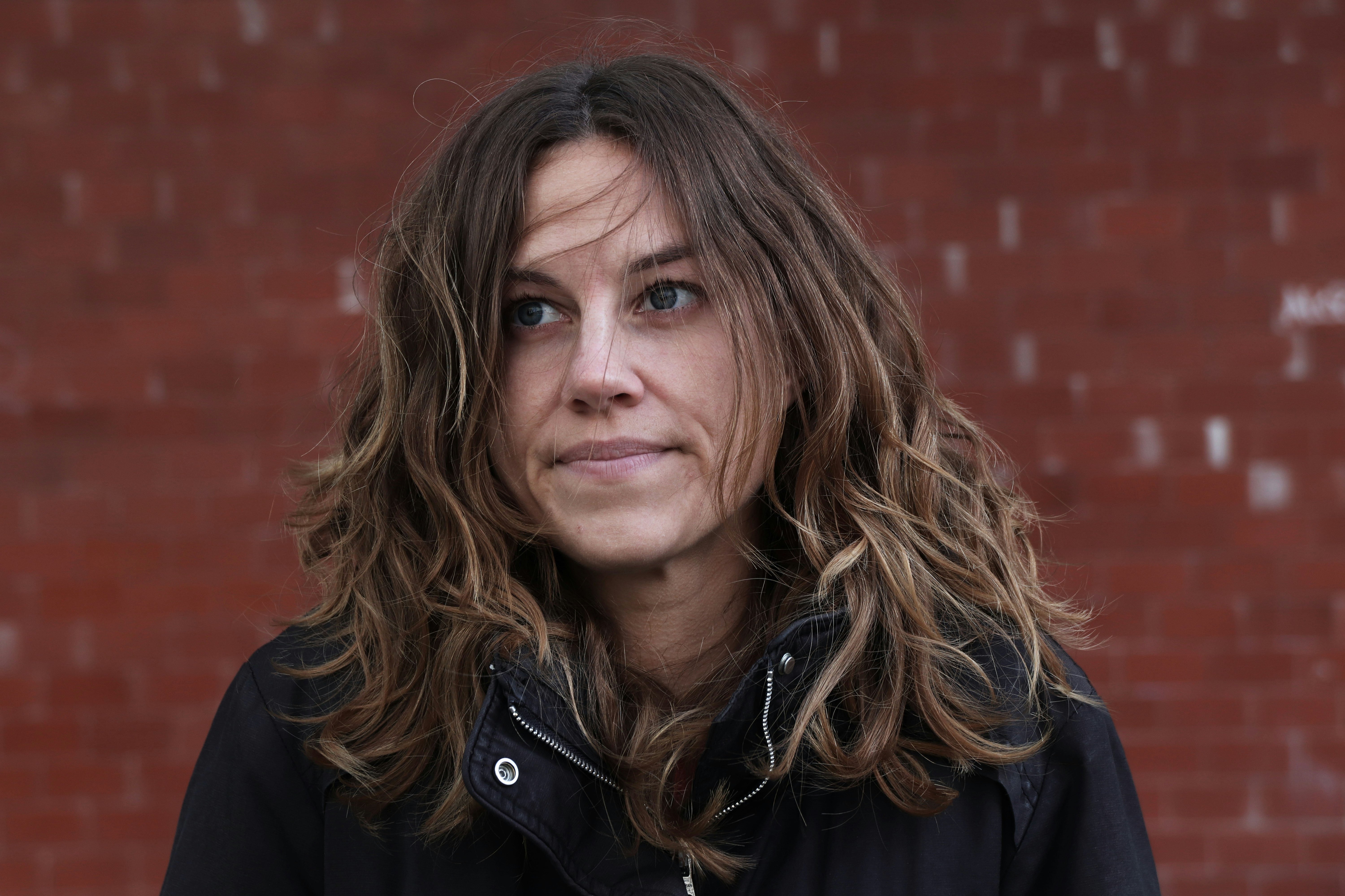 Une femme debout devant un mur de briques