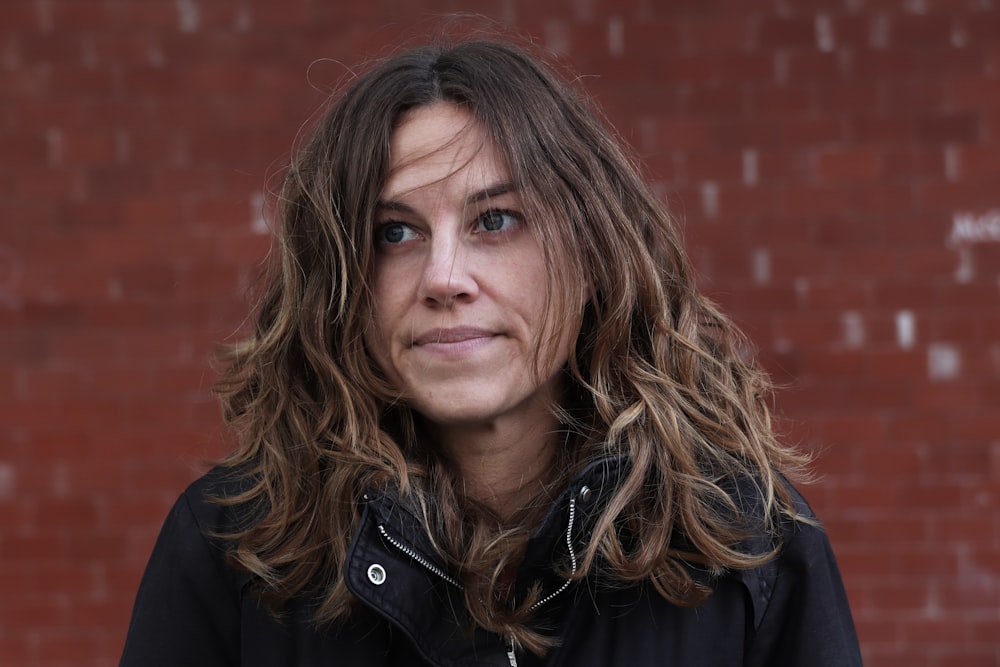 a woman standing in front of a brick wall