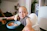 A smiling toddler sitting happily at a high chair enjoying a healthy meal.