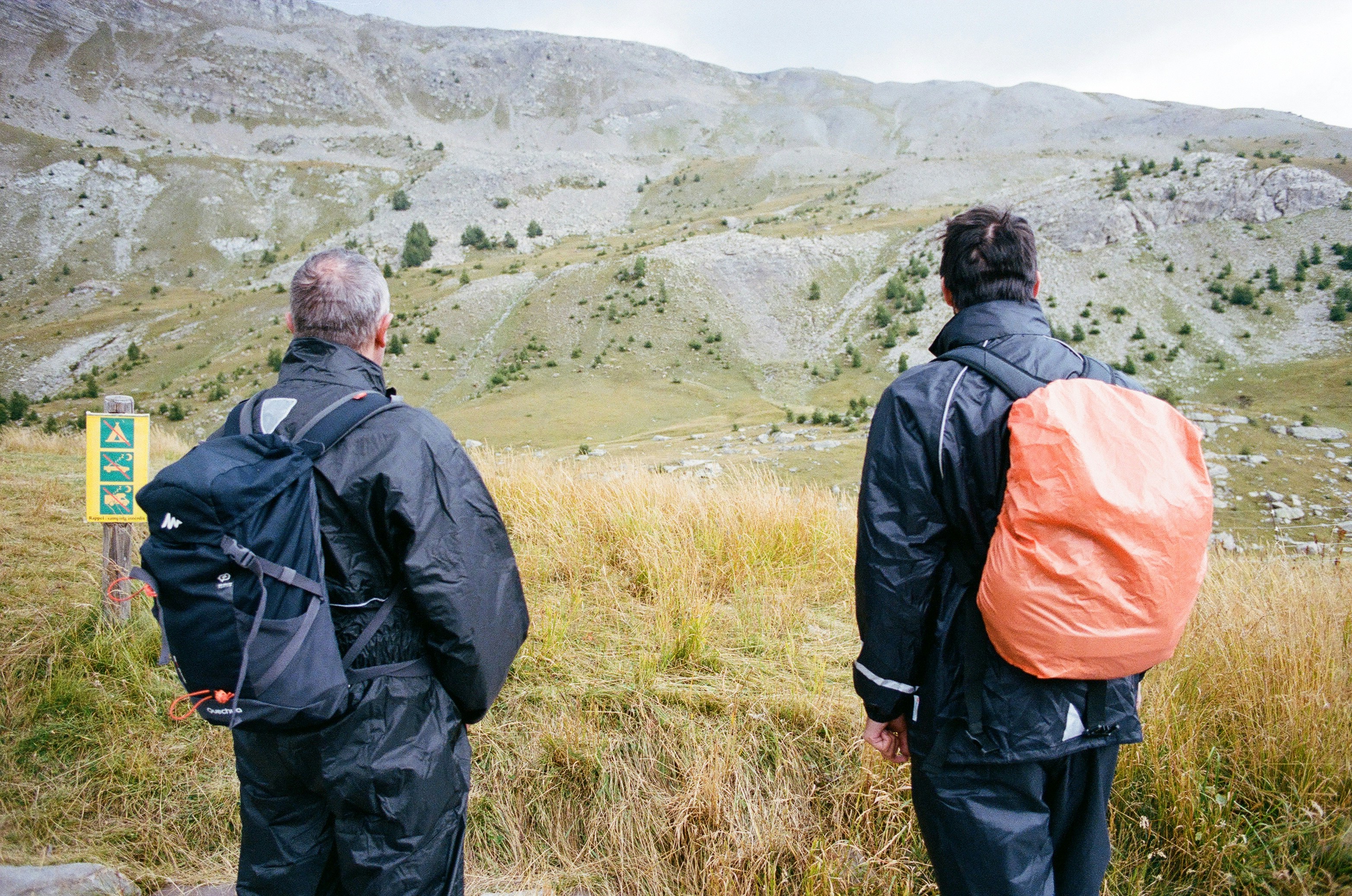 two men with backpacks standing on a hill