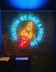 a neon sign that says houston we have a rocket on it