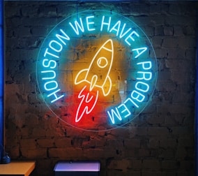 a neon sign that says houston we have a rocket on it