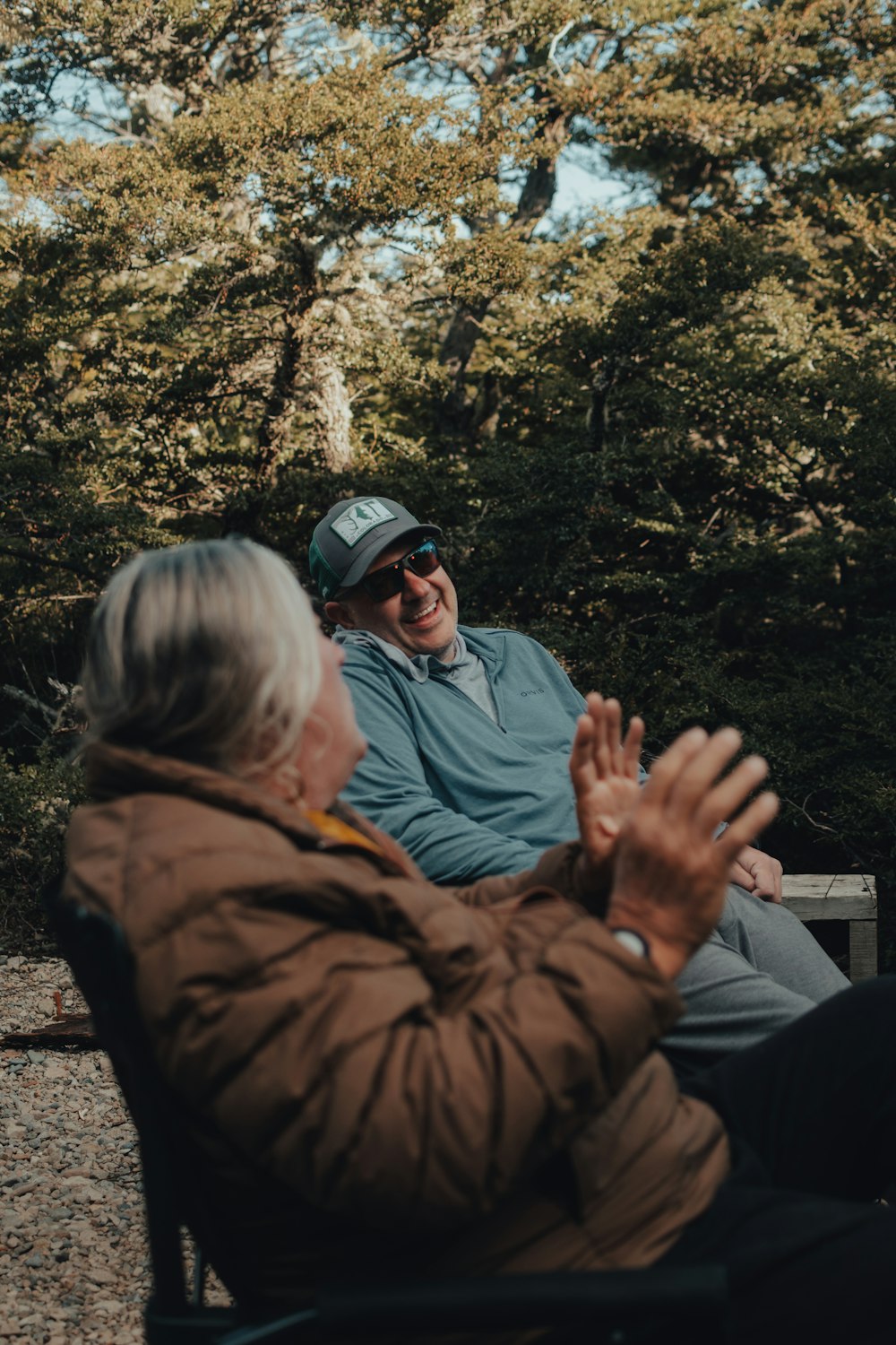 a man and a woman sitting on a bench in the woods