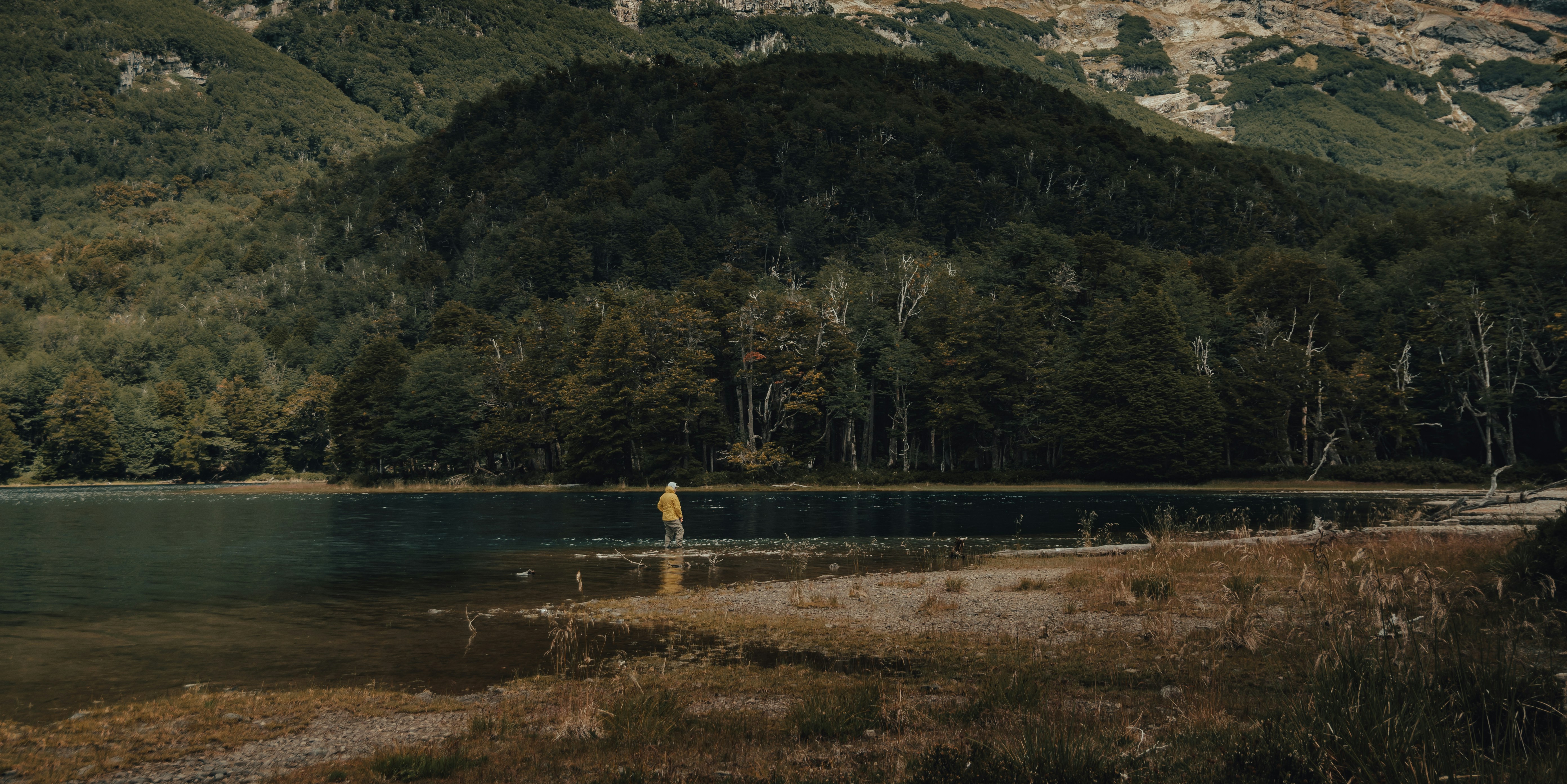 a person standing in a lake surrounded by mountains