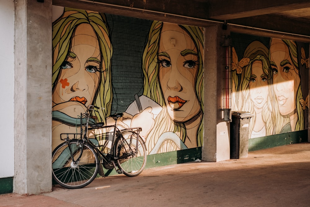 a bike parked next to a wall with a painting on it