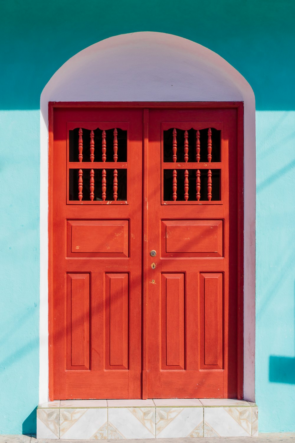 a red door with a white arch on a blue wall