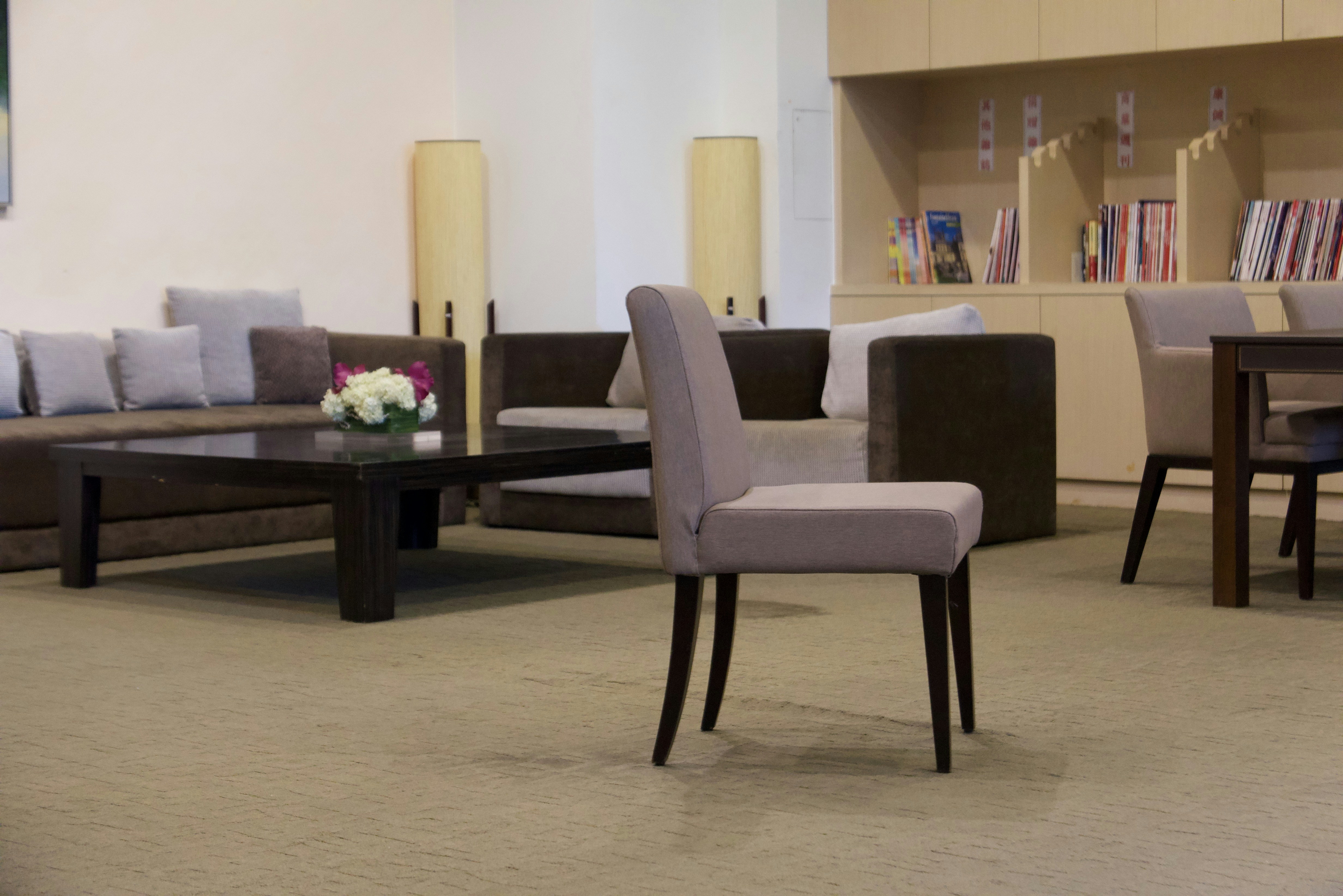Modern hotel lobby with sofas and a wood bookshelf.