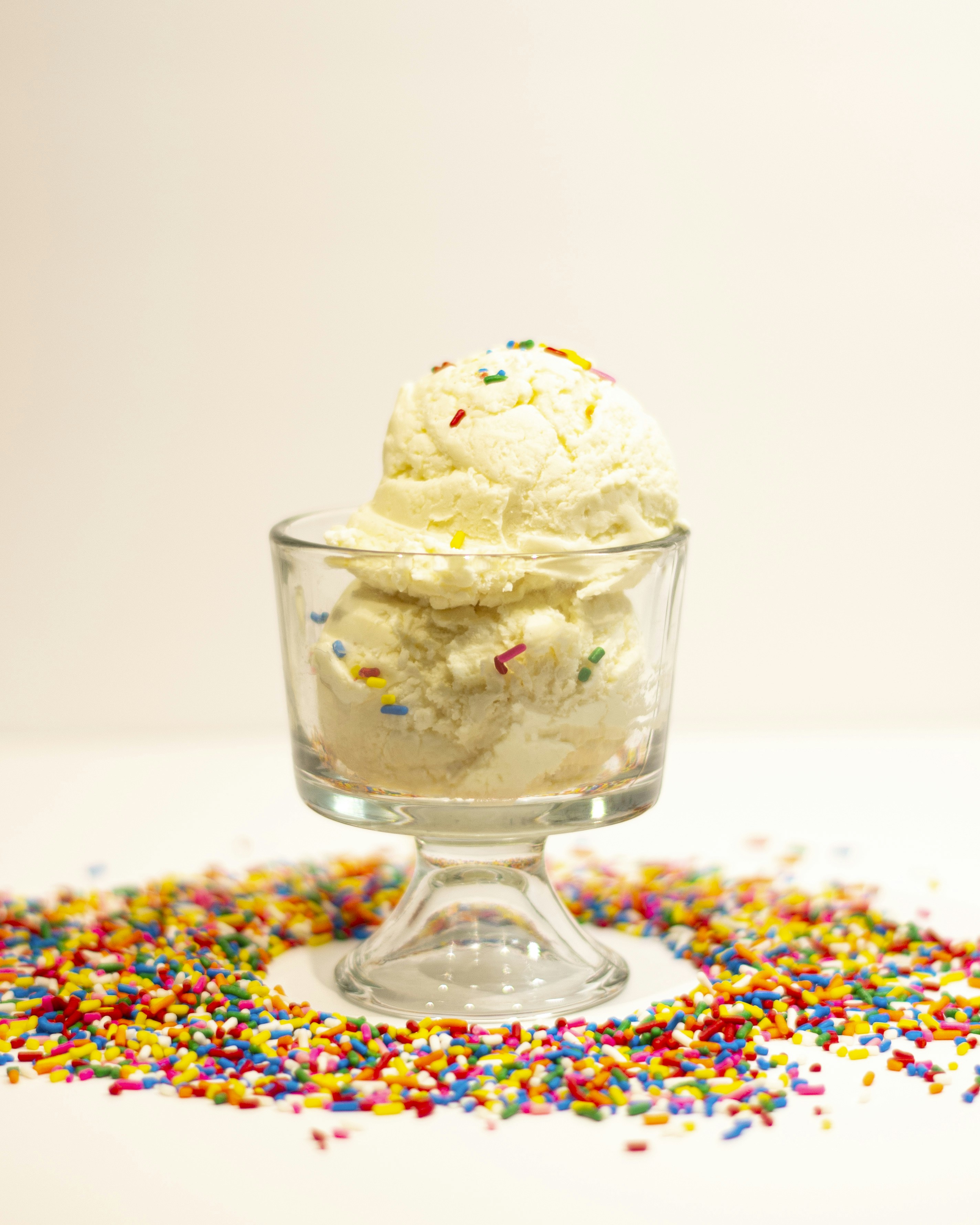 vanilla ice cream with rainbow sprinkles inside a sundae glass