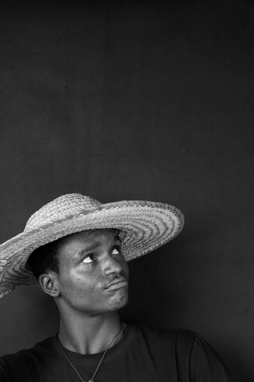 a black and white photo of a man wearing a straw hat