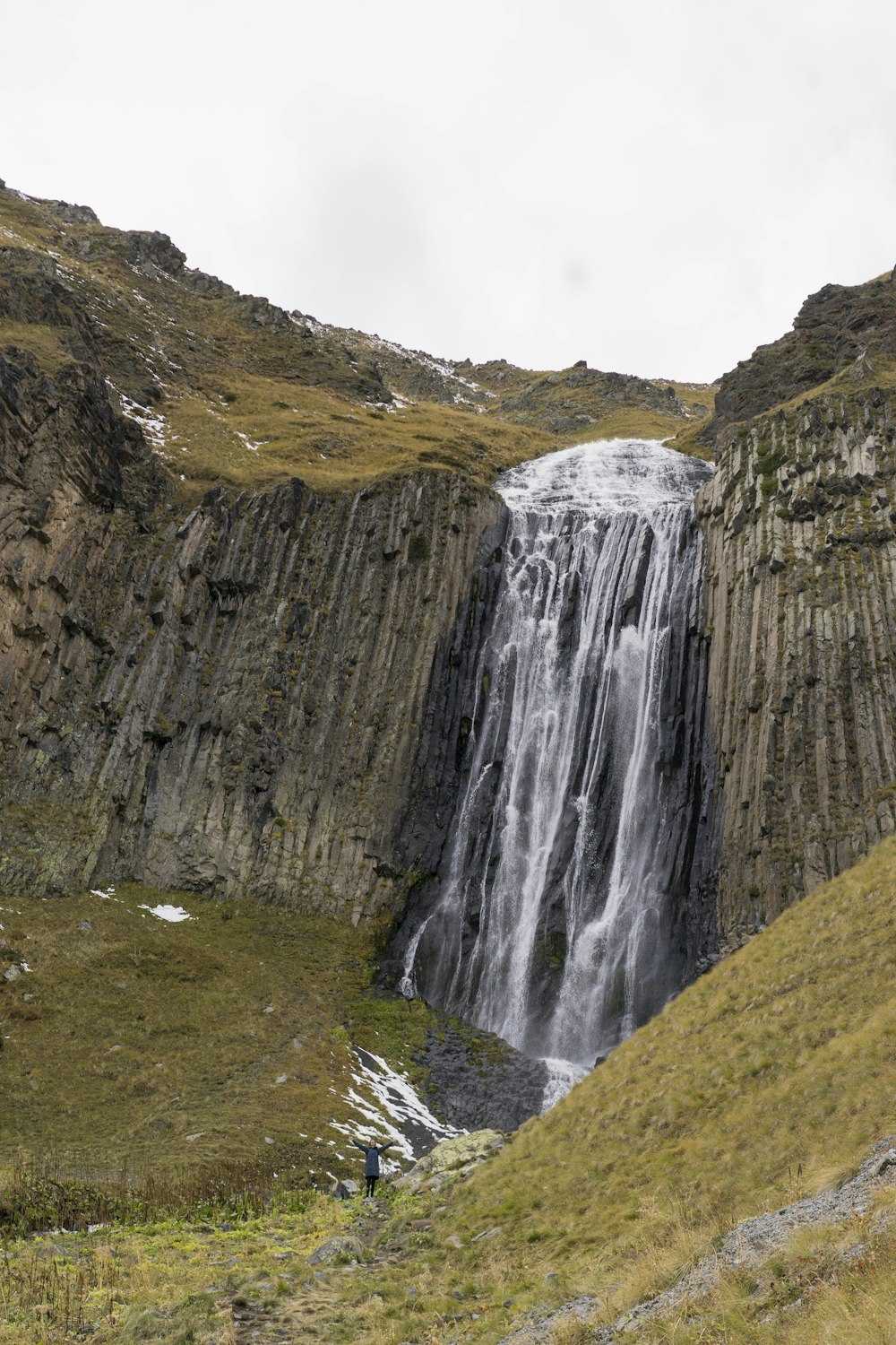 a waterfall in the middle of a grassy area