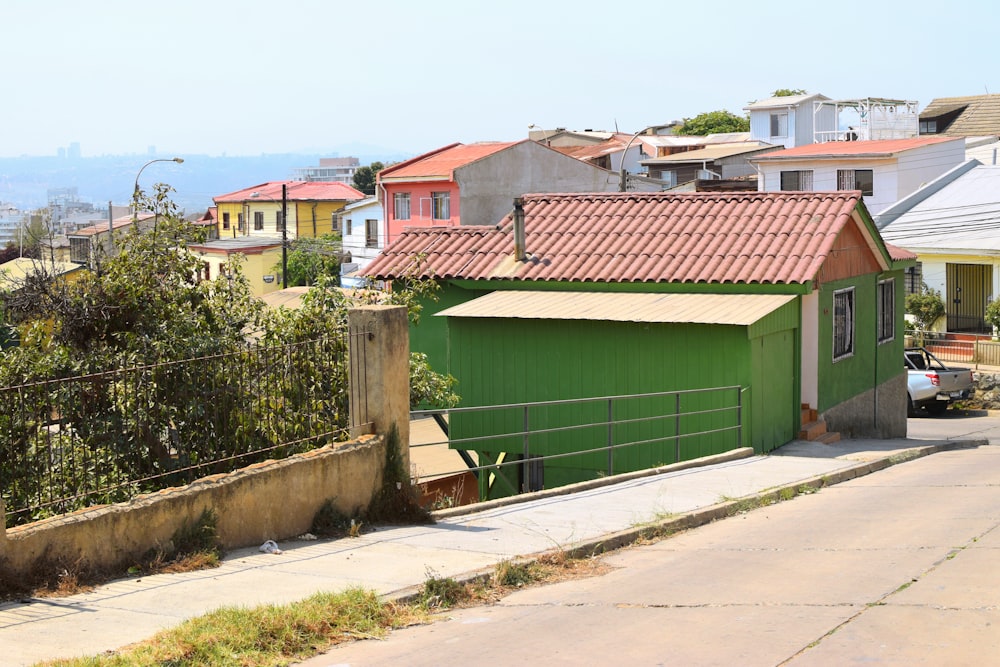 a green building with a red roof next to a fence