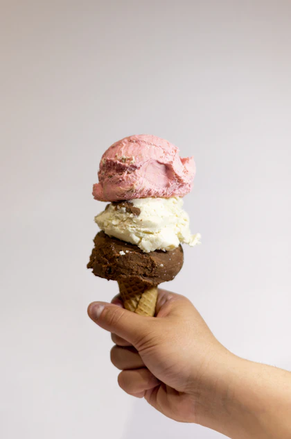 A stacked pink and vanilla ice cream cone to take home