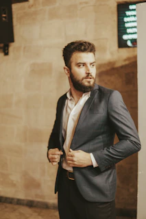 a man wearing a suit and tie standing in front of a wall