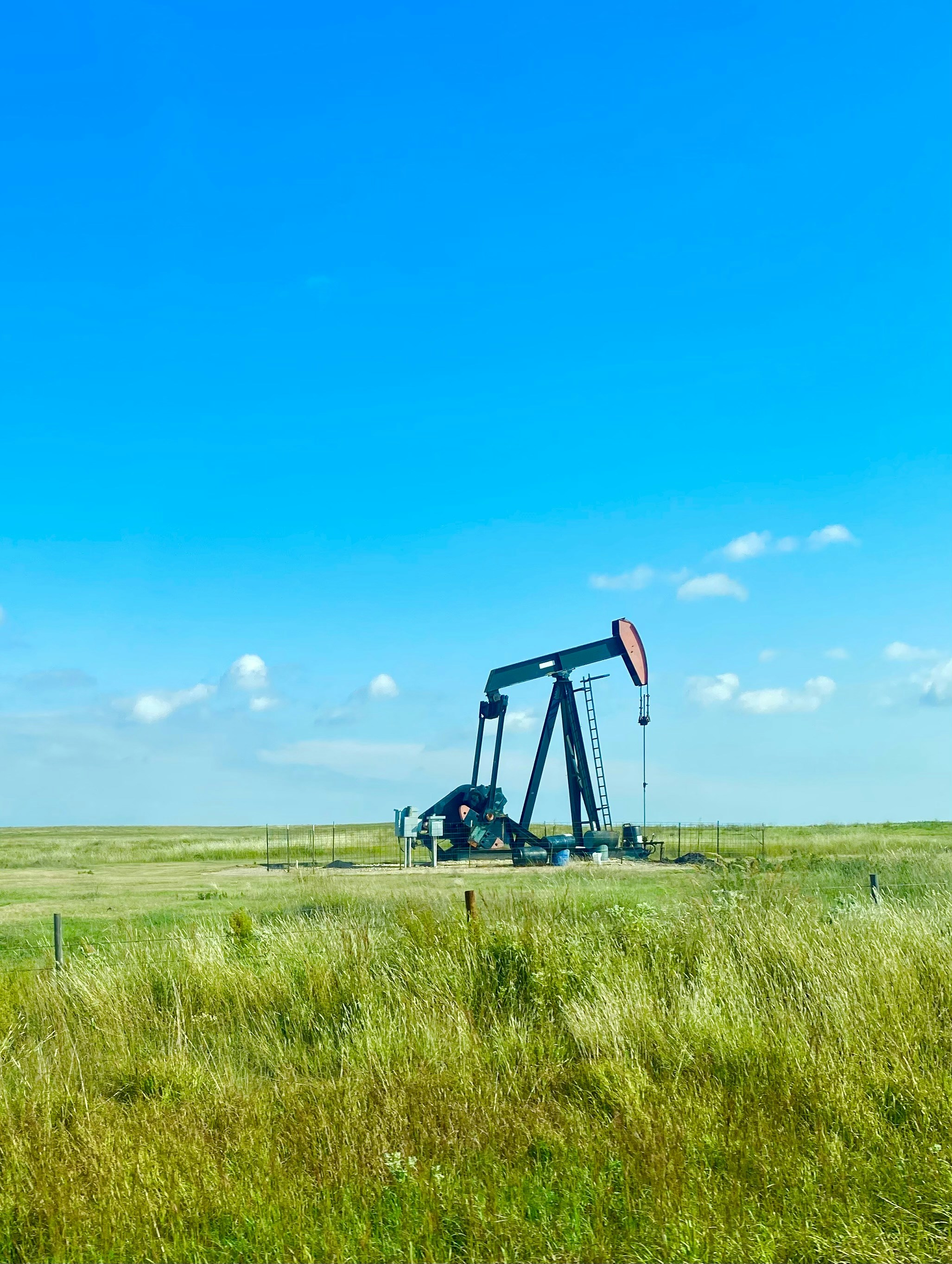 Oil well pump jack operating in Texas field, bright daylight, industrial machinery