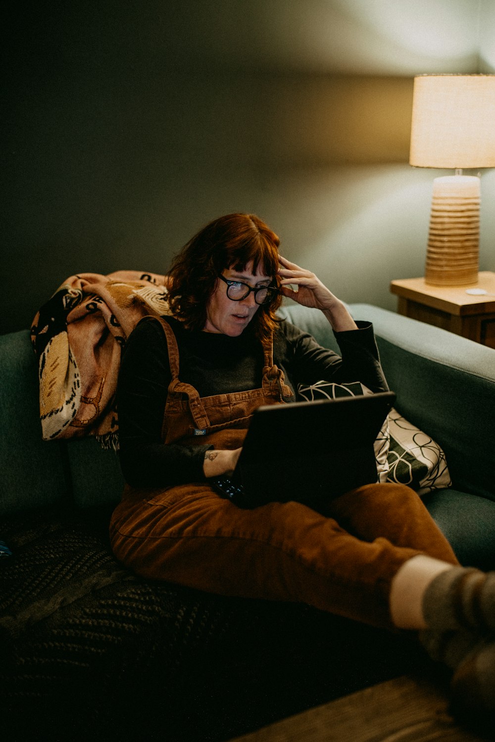 a woman sitting on a couch using a laptop computer