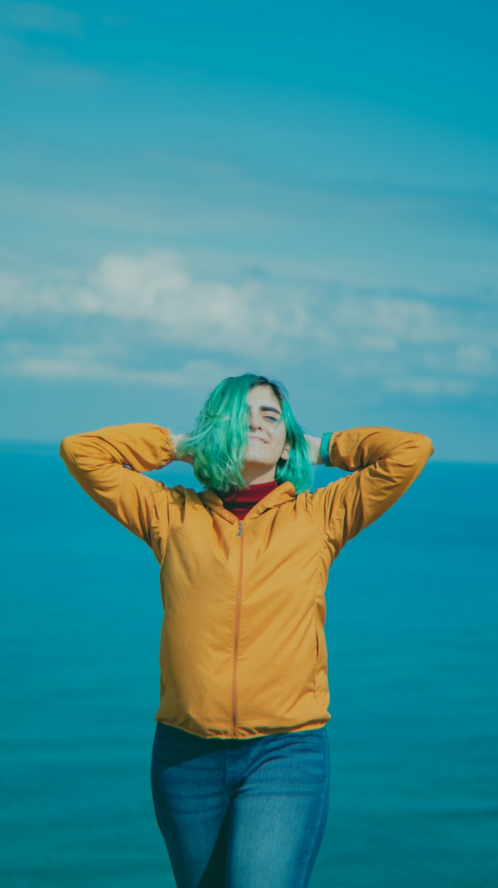 a woman with green hair standing on a beach
