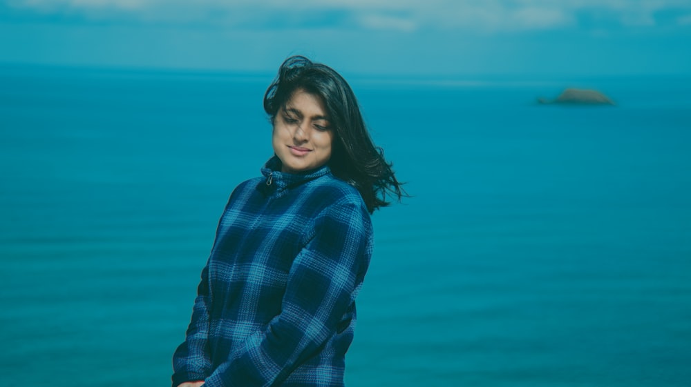 a woman standing in front of a body of water