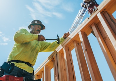 a man in a hard hat and safety gear working on a wooden structure
