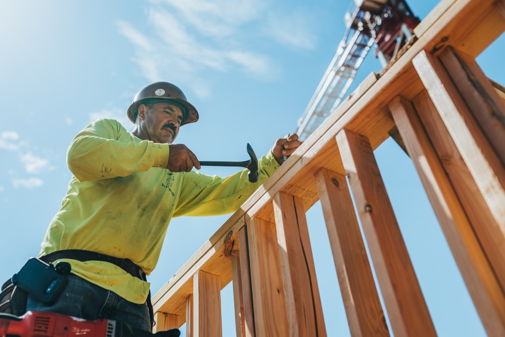 a man in a hard hat and safety gear working on a wooden structure