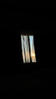 A window with sheer curtains gently swaying, revealing a hint of the outside world.