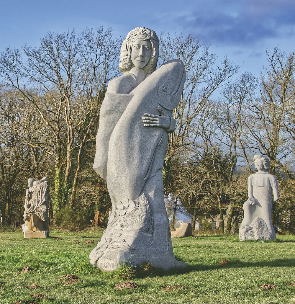 a statue of a woman holding a fish in a park