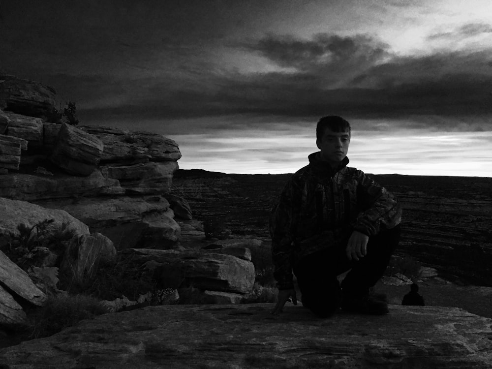 a man sitting on top of a rocky cliff