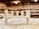 A partially assembled wooden furniture piece rests on a workshop table, surrounded by wood shavings. The background is a blurred view of a workshop, with shelves and tools visible.