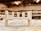 A partially assembled wooden furniture piece rests on a workshop table, surrounded by wood shavings. The background is a blurred view of a workshop, with shelves and tools visible.