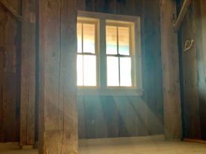 Sunlight filtering through wooden slats inside a rustic homestay room.