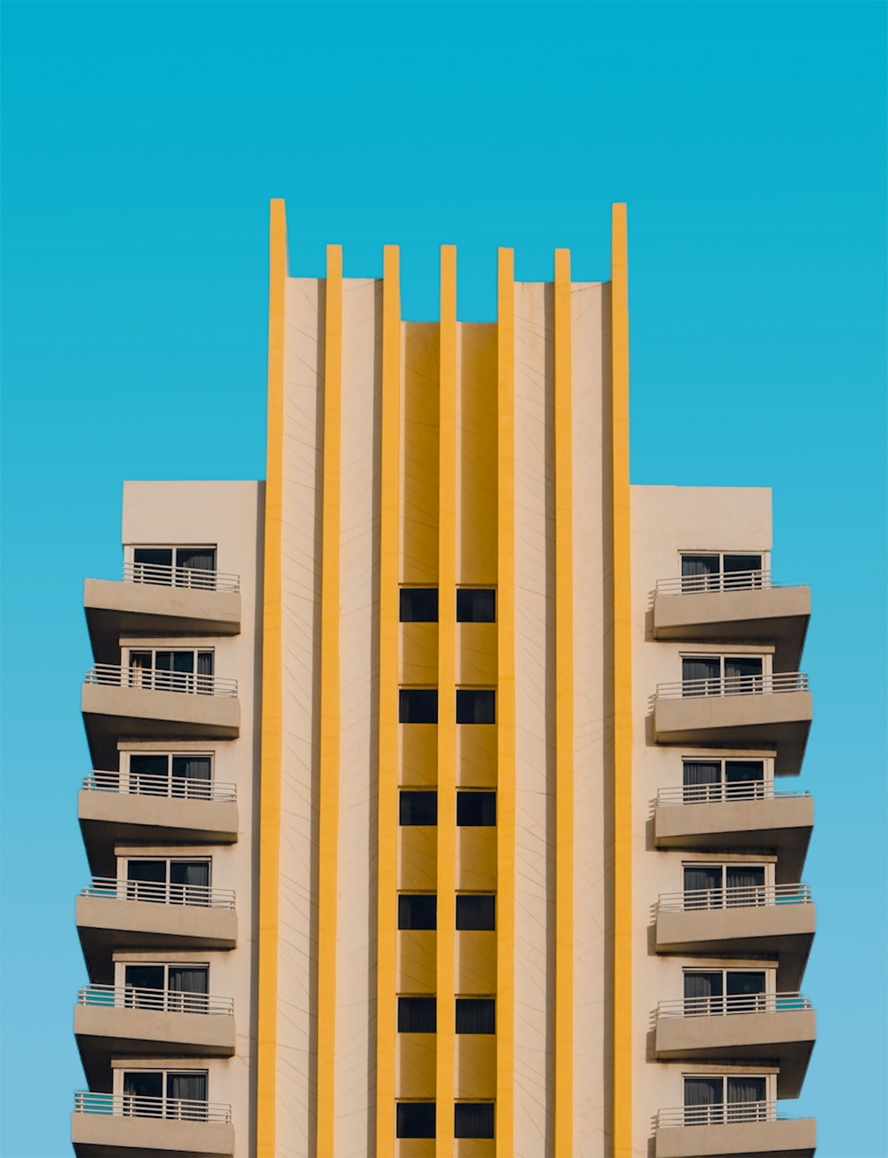 a tall yellow building with balconies on top of it