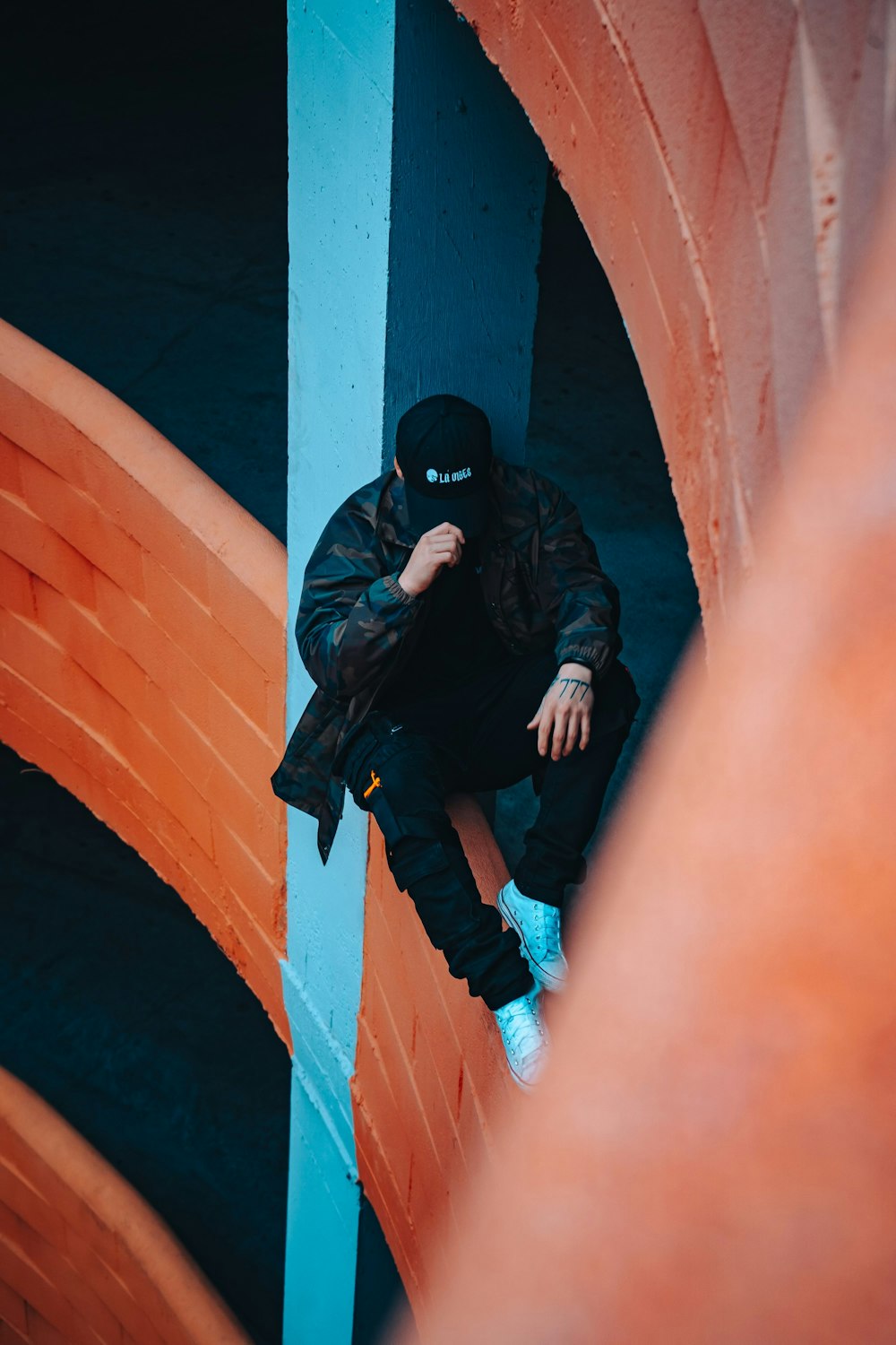 a man in a black jacket sitting on a wall