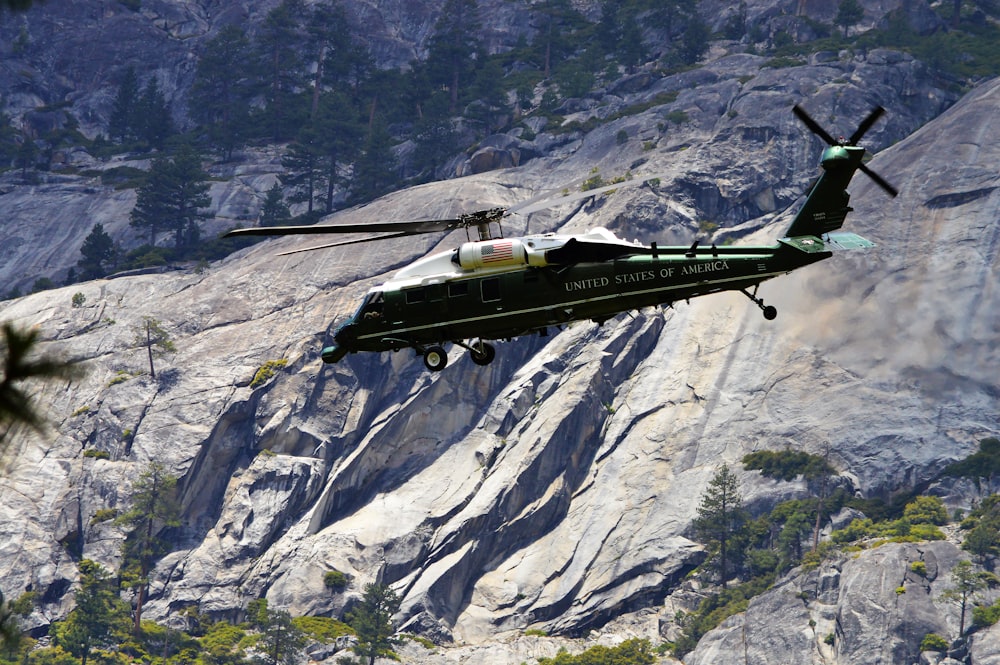 a helicopter is flying over a mountain side