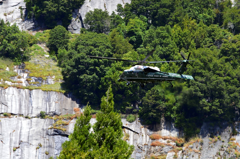 a helicopter flying over a lush green forest