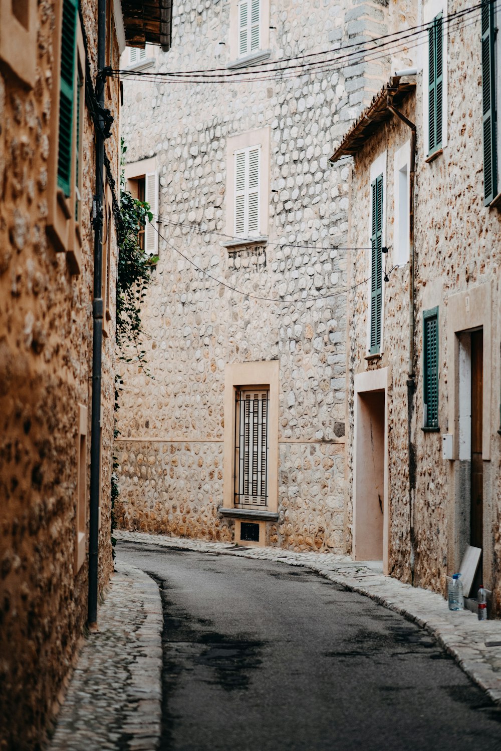 a narrow street with stone buildings and green shutters